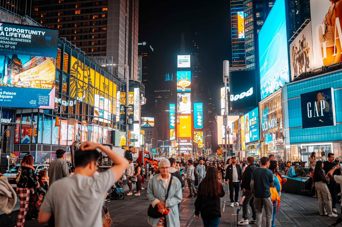 Times Square, New York, 2024 &mdash; crowds on the plaza at night beneath walls of illuminated billboards