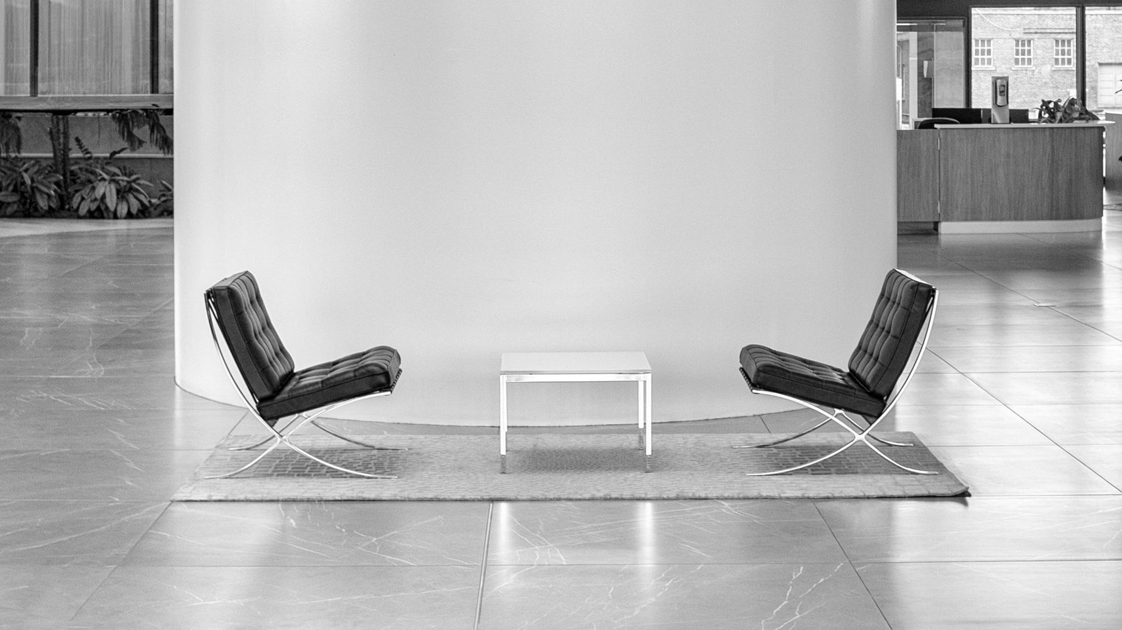 Two black leather chairs facing each other across a low table in a bright, minimal lobby